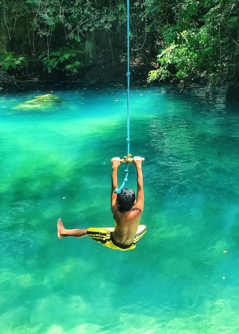 A person swinging into a body of water.