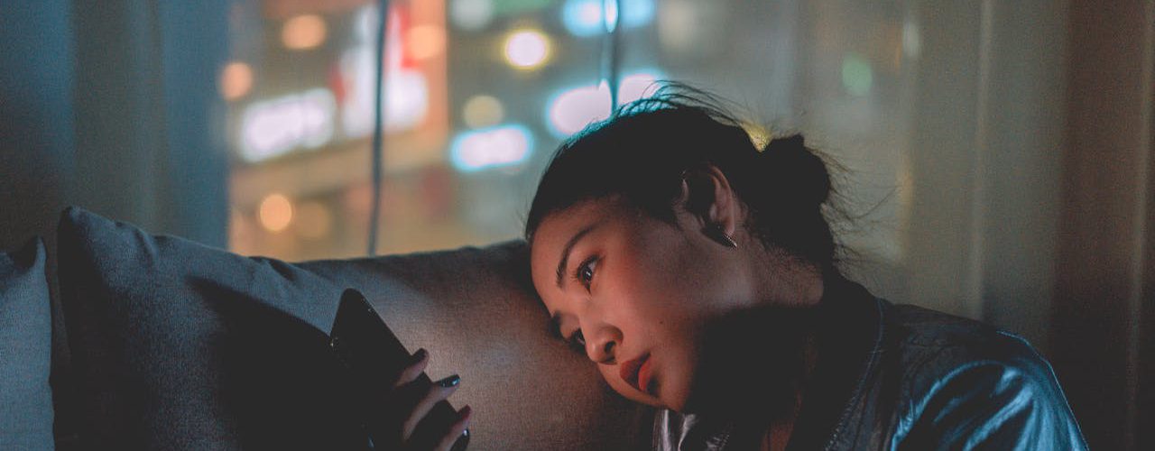 A woman relaxing on a sofa while using her phone.