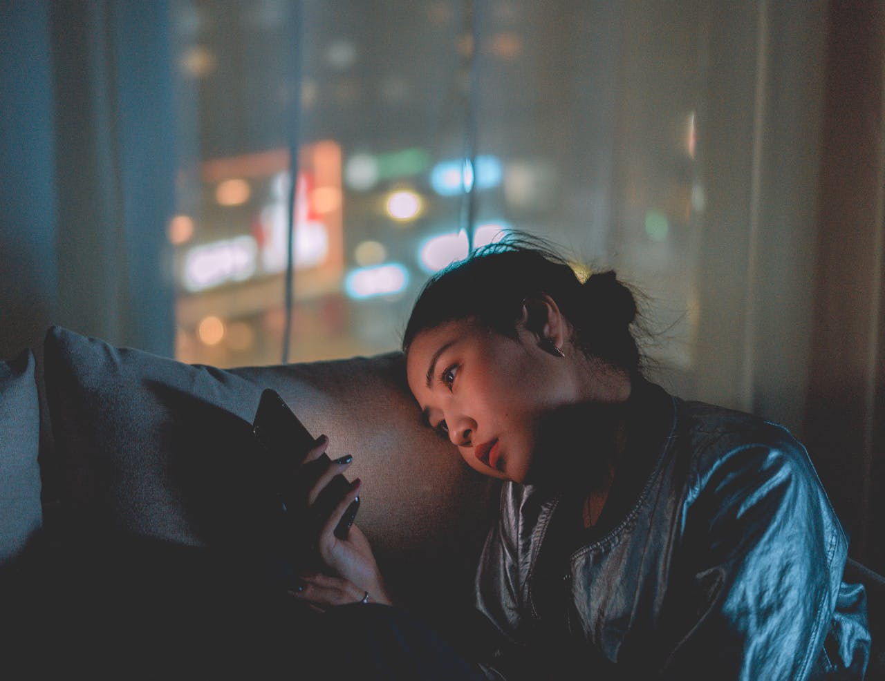 A woman relaxing on a sofa while using her phone.