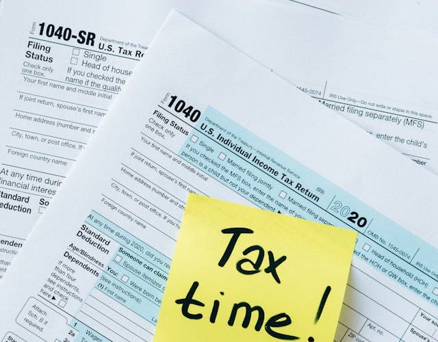 A sticky note that says "tax time!" It's placed on a stack of documents.